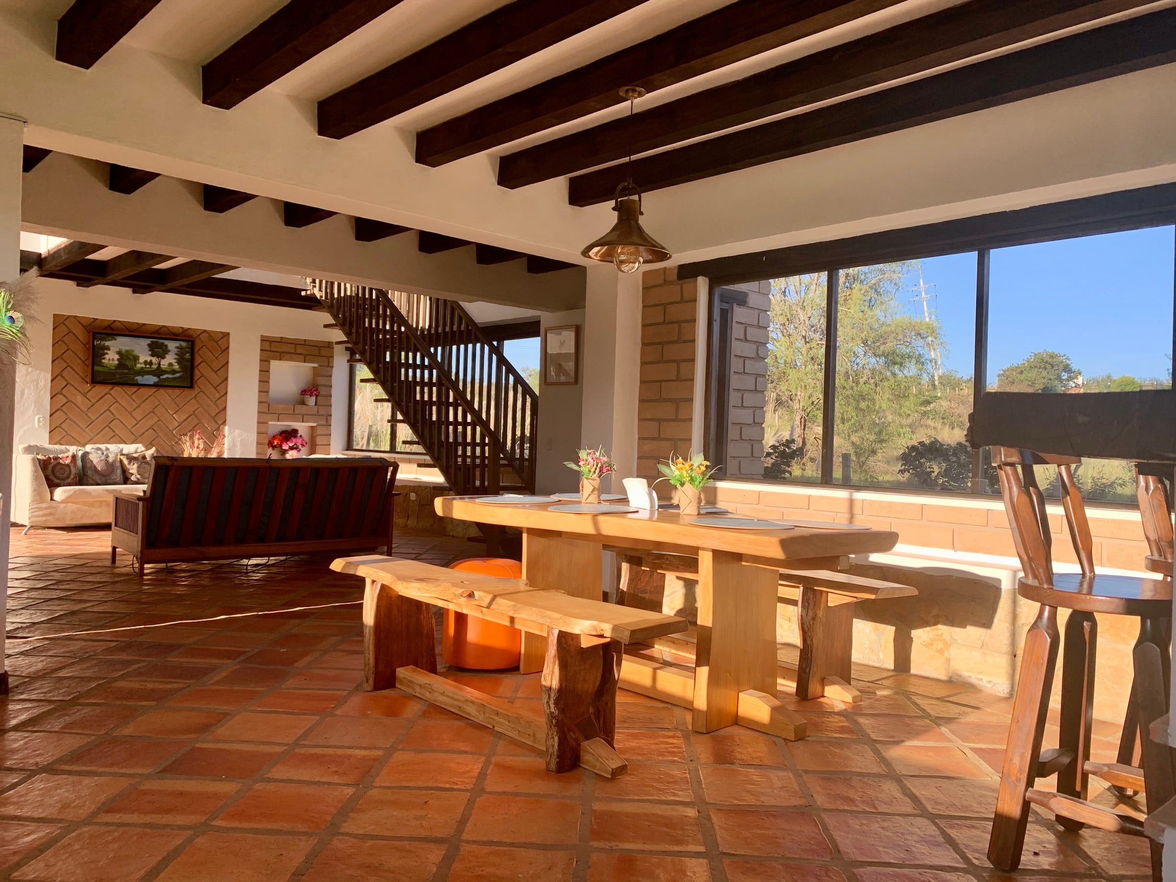 Comedor con bancas de madera frente a un ventanal que enmarca el paisaje de la vereda Ritoque