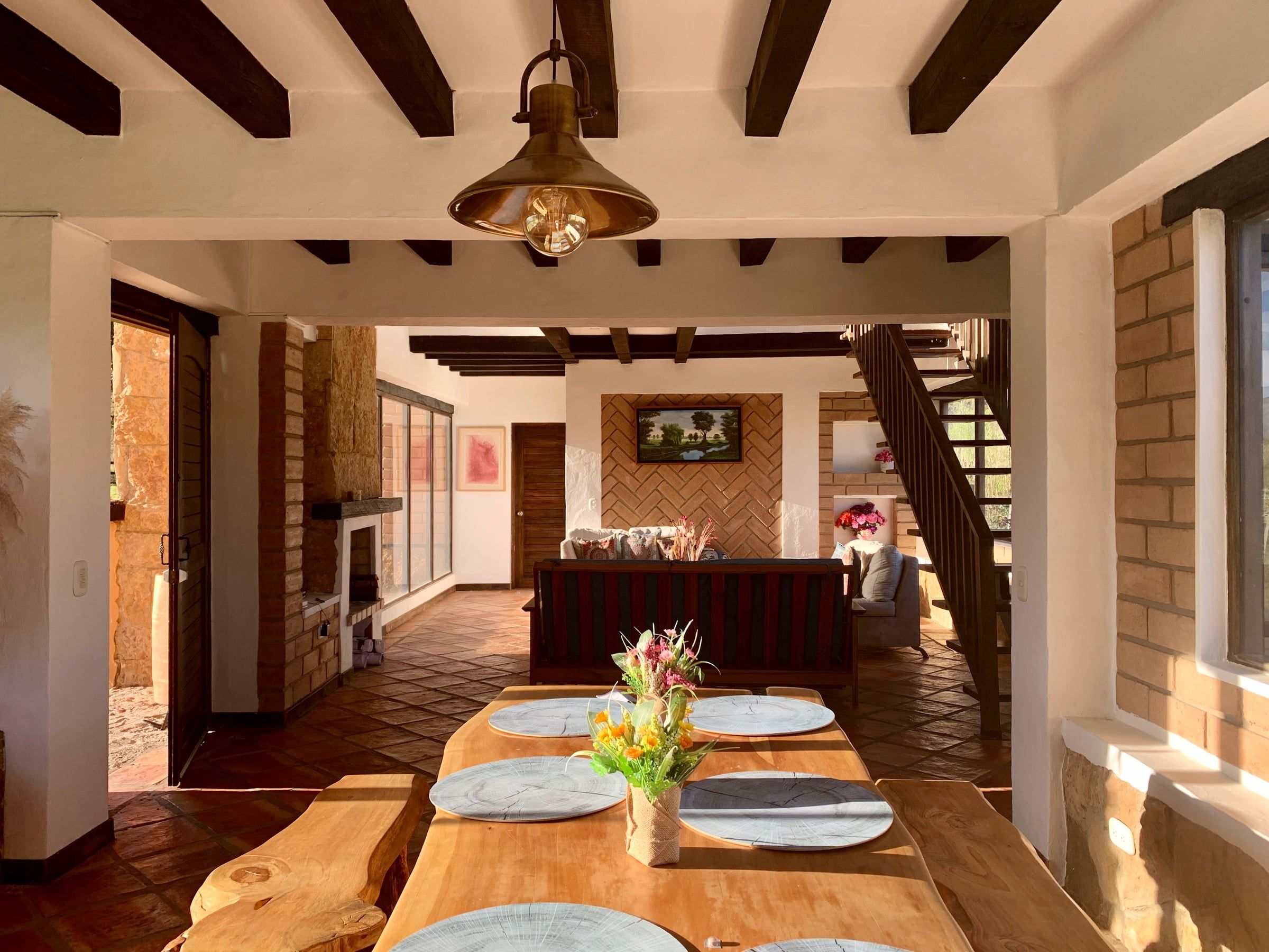 Comedor de la Casa del Lago con mesa de madera maciza, vigas de madera a la vista y piso de baldosa de barro