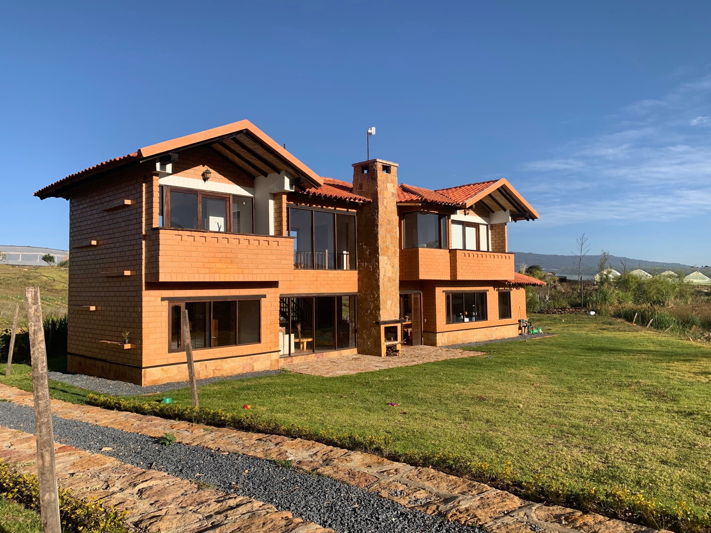 Vista lateral de la Casa del Lago con el volumen de la chimenea y los balcones de madera sobre muros de BTC
