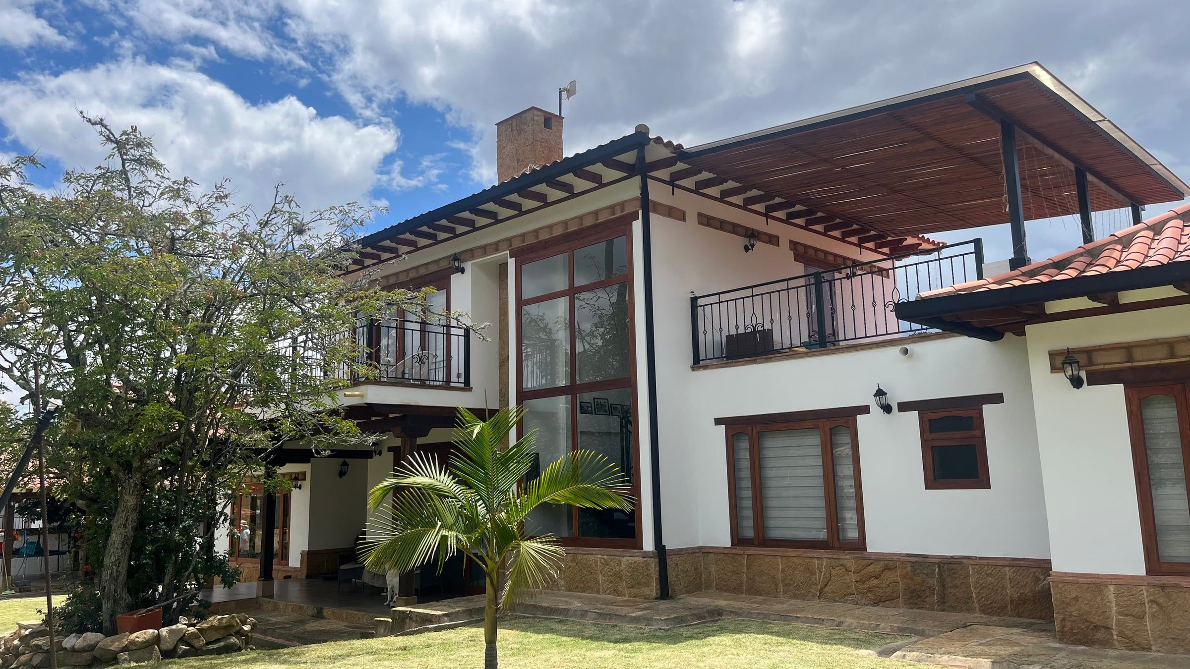 Fachada posterior con ventanales de doble altura, balcón y jardín