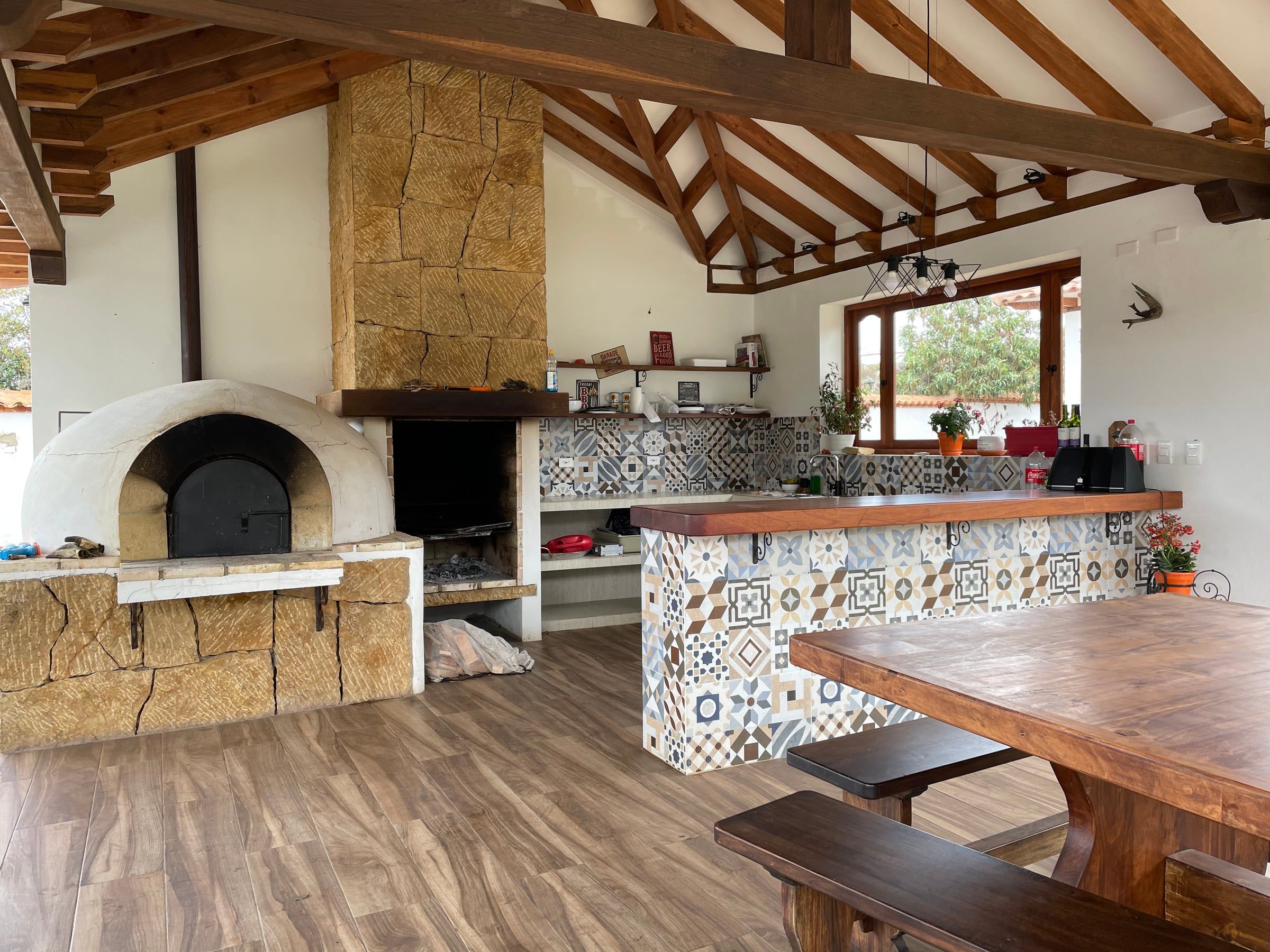 Zona social de la Casa Dividivi con horno de leña, barra de baldosa decorada y cubierta de madera