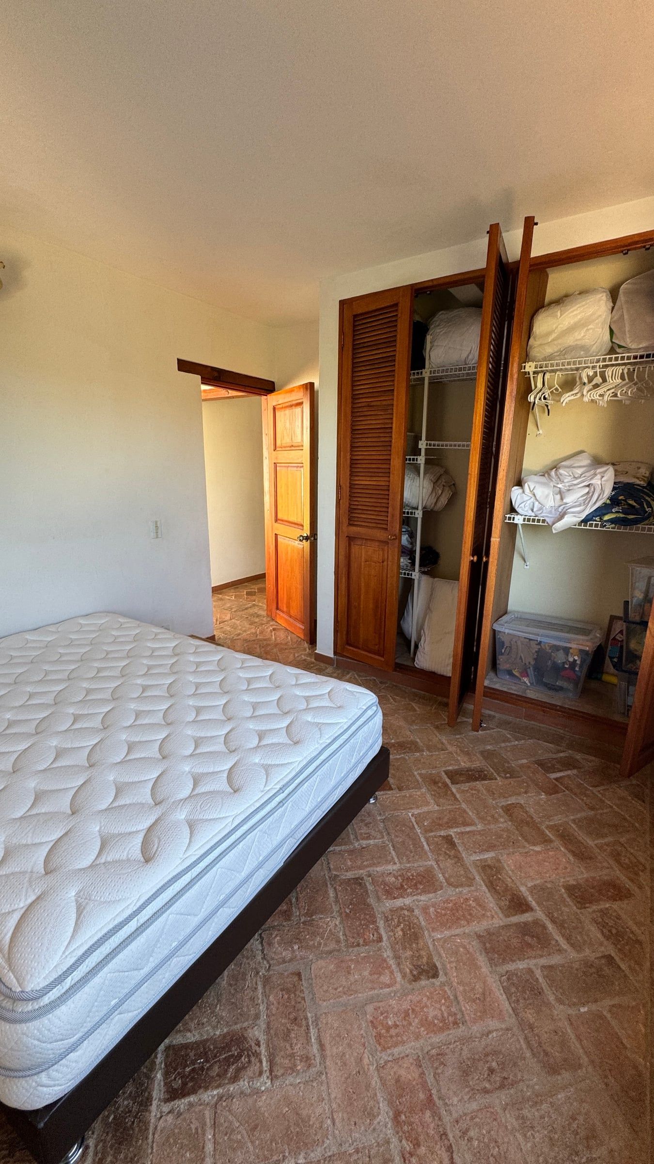 Casa Nido Verde antes de la remodelación: habitación con clóset abierto de madera y piso de ladrillo