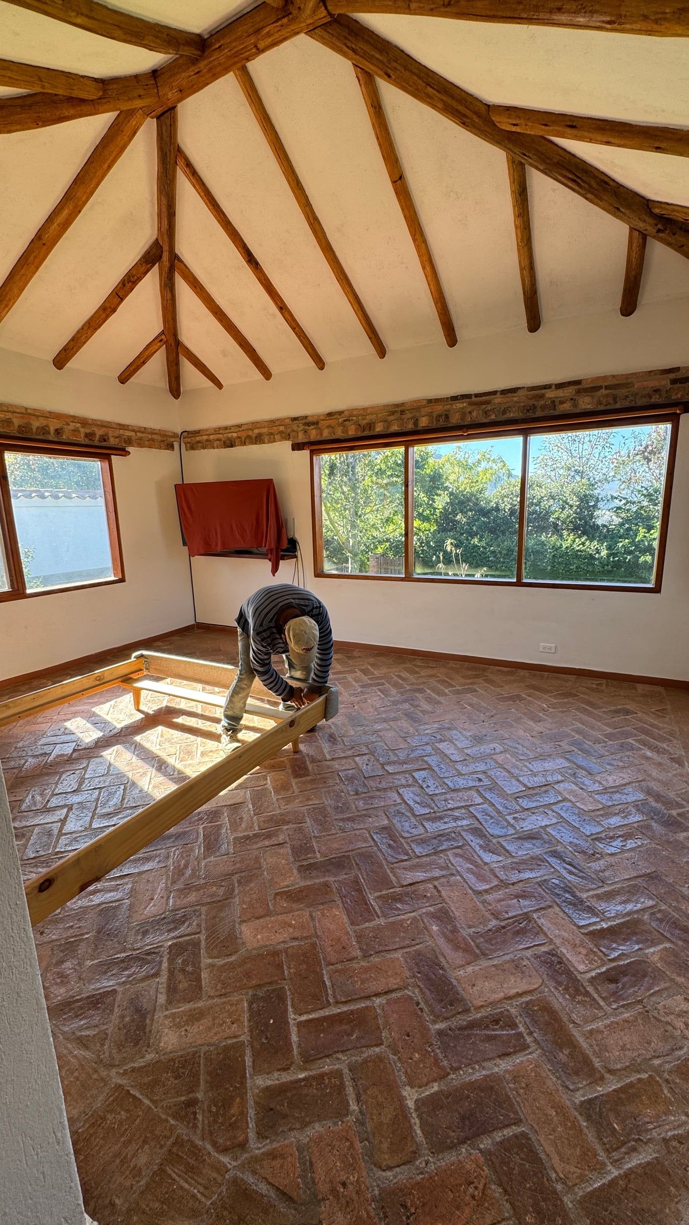 Casa Nido Verde durante la obra: habitación de cubierta octogonal de vigas de madera con piso de ladrillo, en remodelación