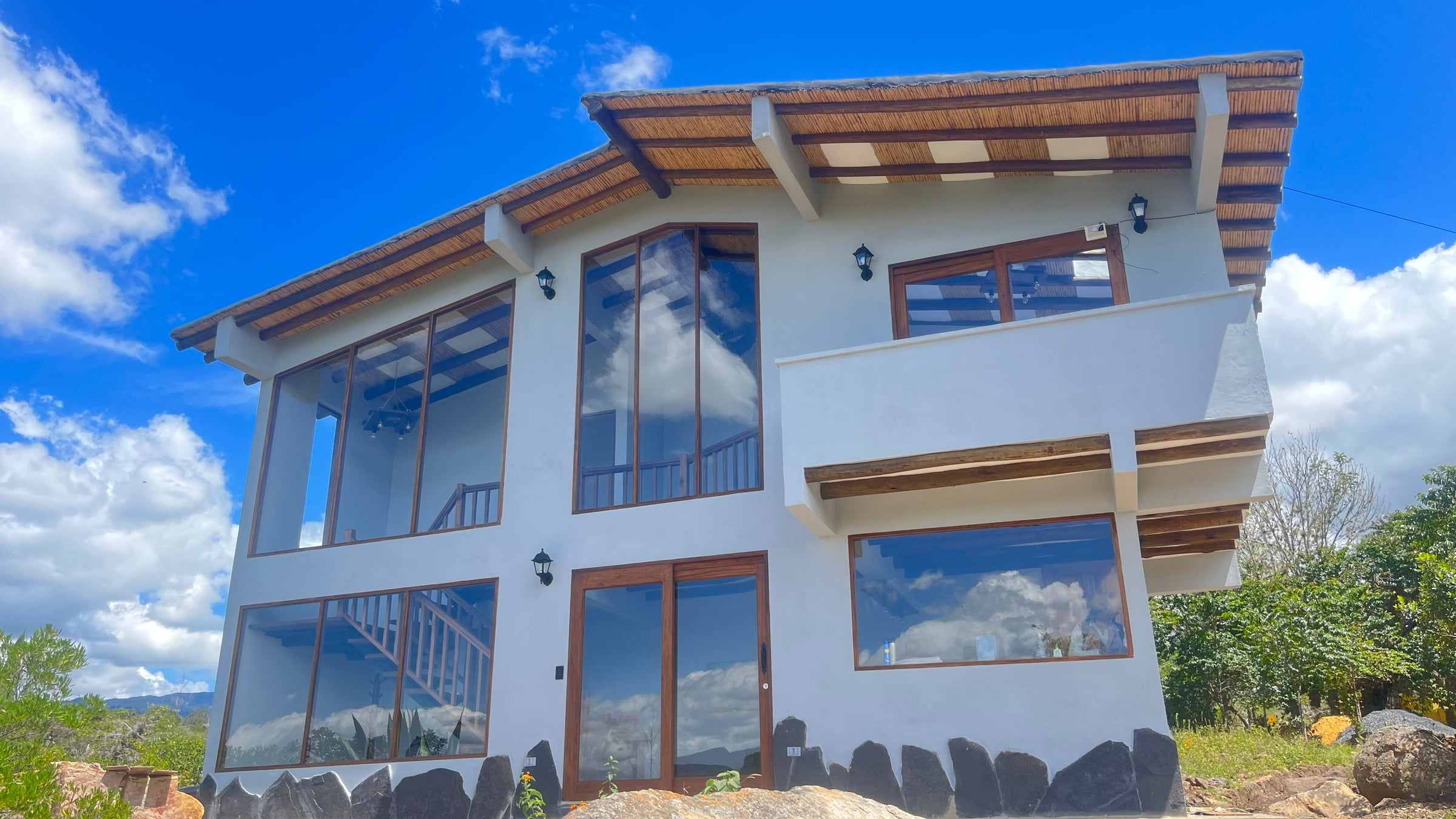 Fachada de Emilia Haus, chalet de dos pisos con grandes ventanales y aleros de madera, en la vereda Hornillas de Santa Sofía, Boyacá